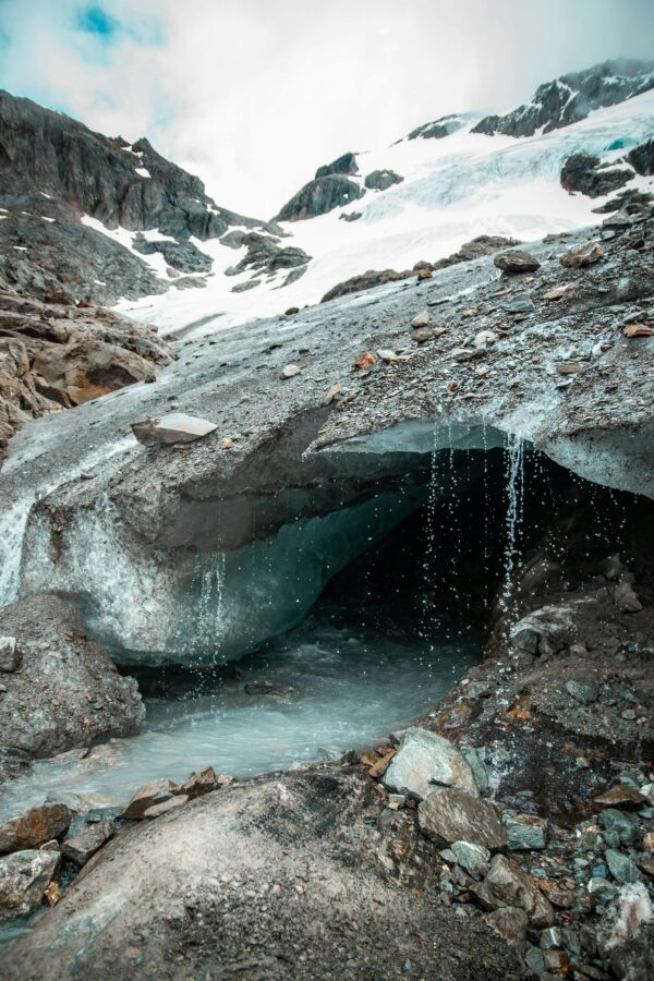 Stunning view of a natural glacier cave with melting snow and water stream in Ushuaia, Argentina.