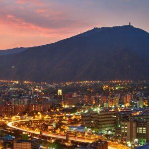 A stunning aerial view of Caracas cityscape at dusk, showcasing the vibrant city lights against the mountainous backdrop.